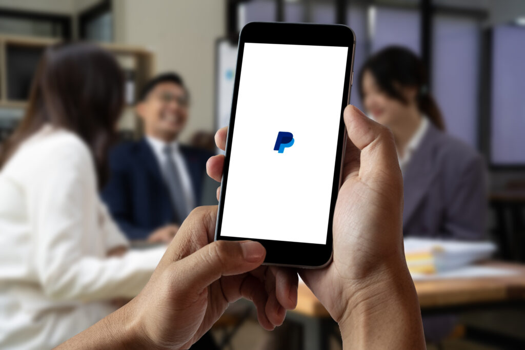Female using Paypal application on a smartphone and laptop in of